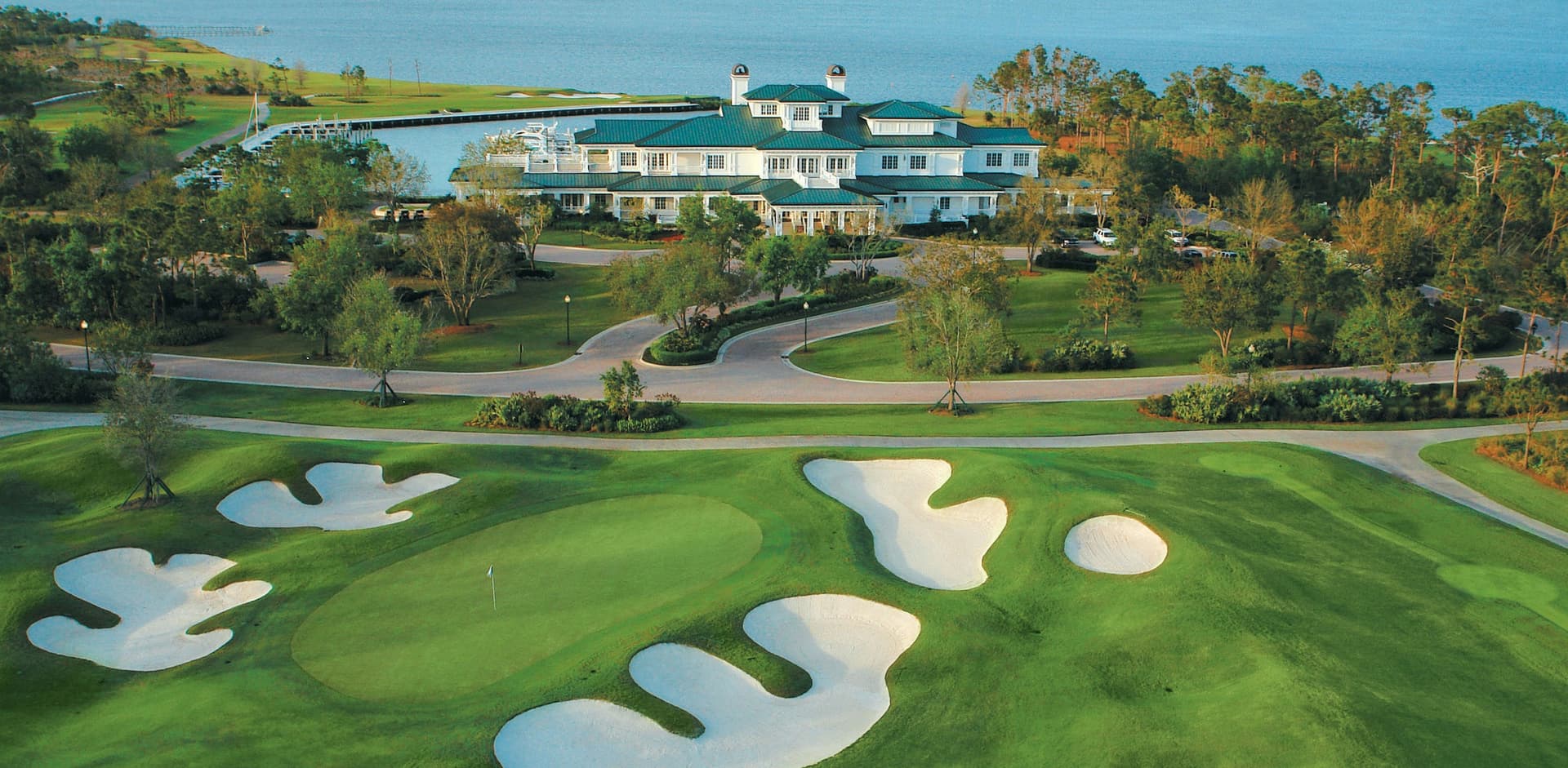 Aerial view of a golf clubhouse, marina, fairways, and water at The Floridian