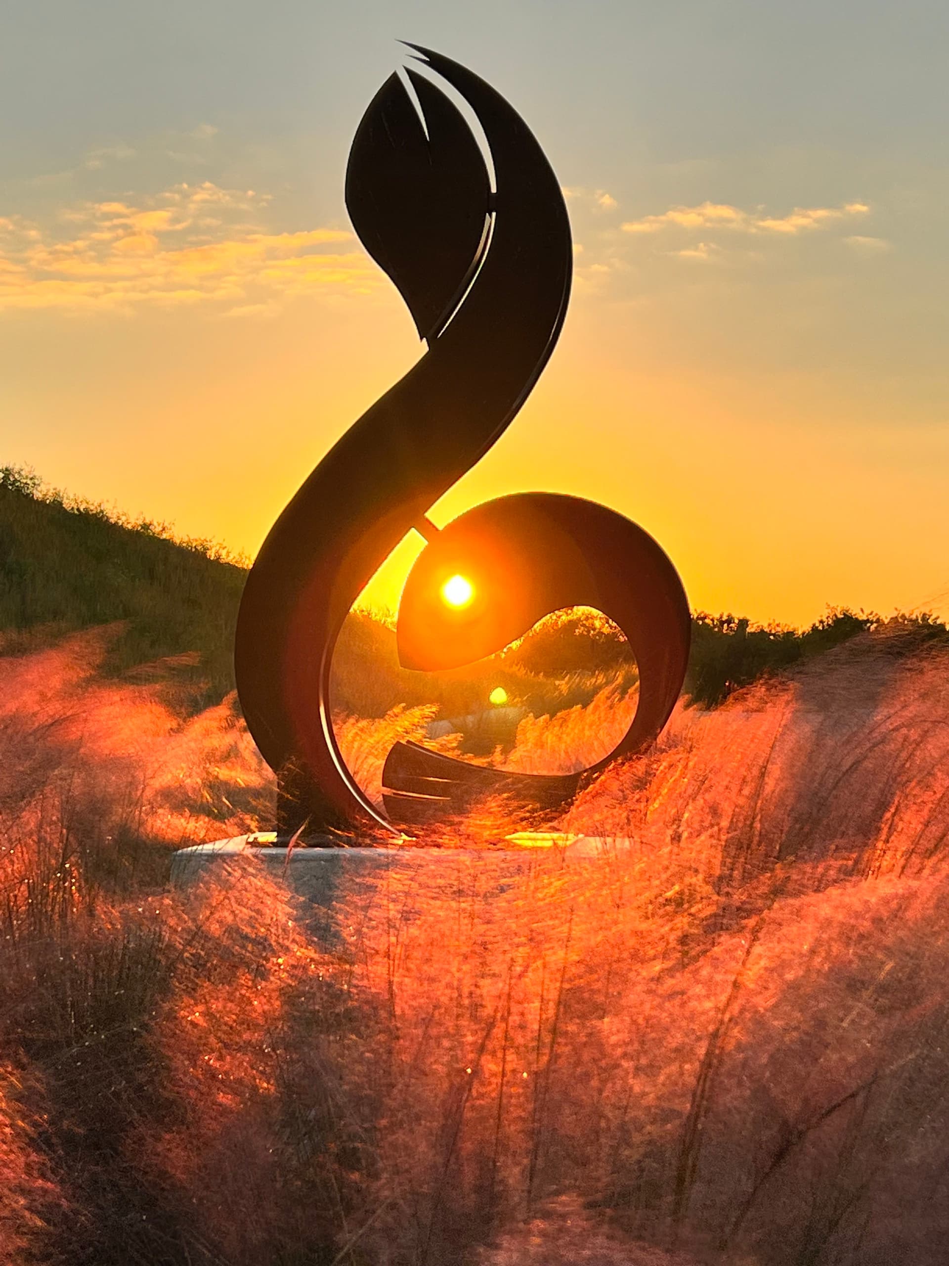 Streamsong Resort sculpture silhouetted at sunset over glowing muhly grass