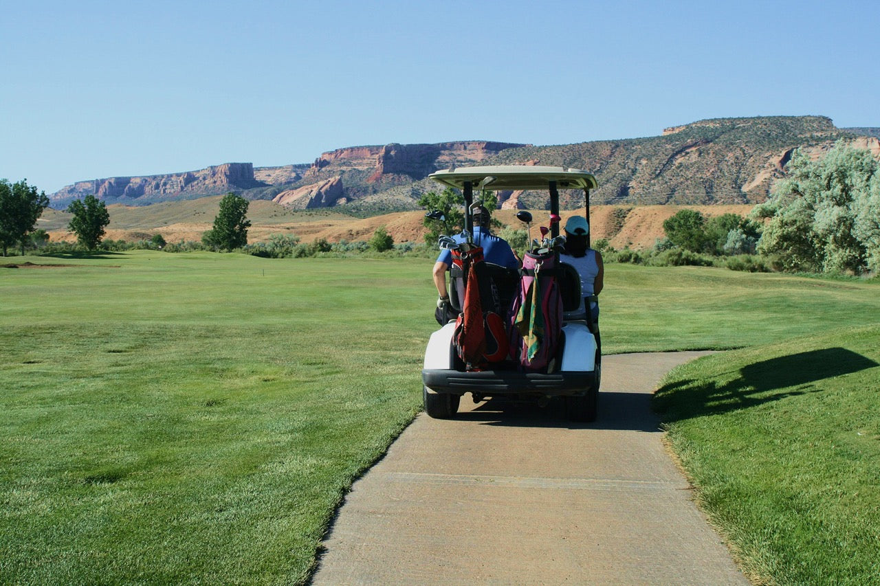 Golf cart driving toward the first tee with golf bags loaded, representing a seamless golf club shipping experience with BagCaddie.